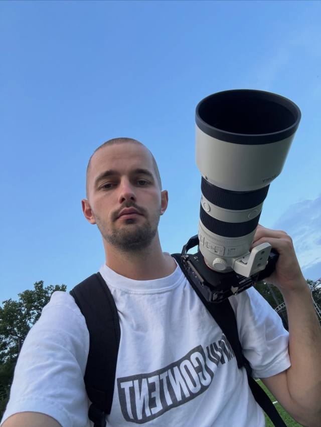 Photographer holding a long telephoto lens outdoors